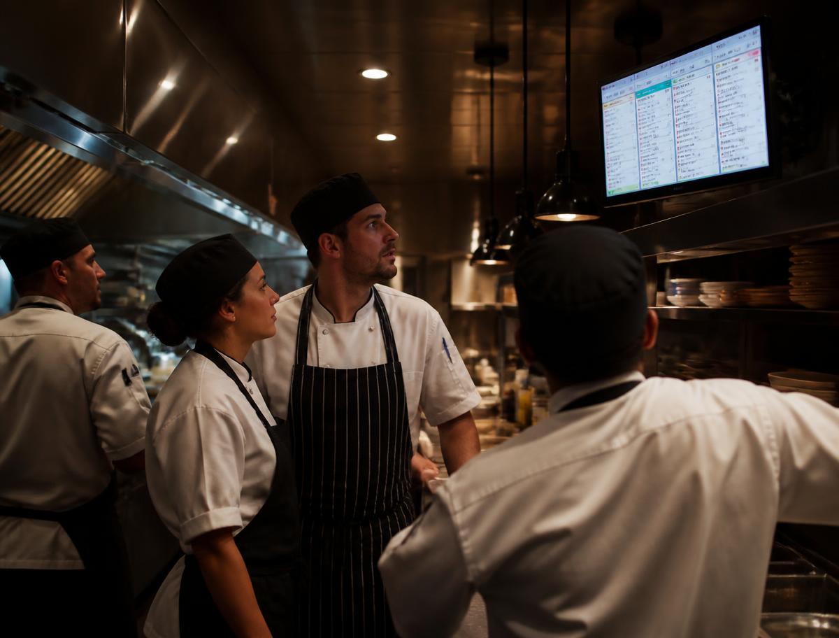 Kitchen brigade working against a mounted kitchen display screen